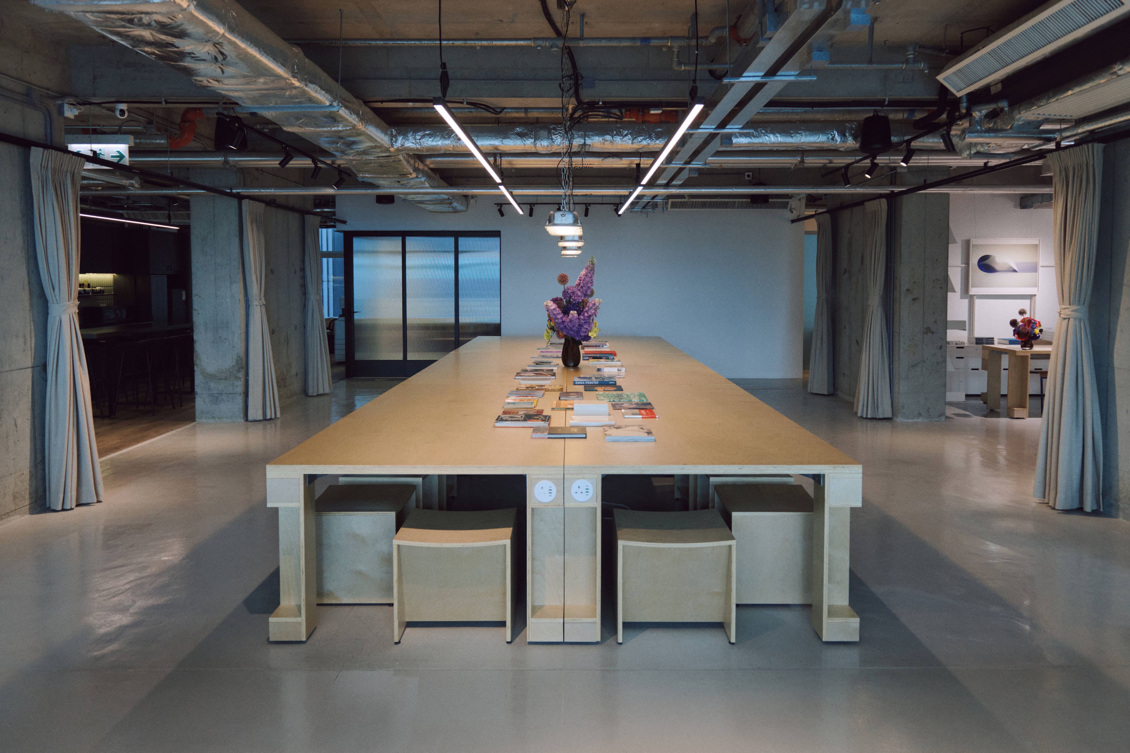 Open hot-desk area with a long communal wooden table
